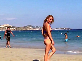 Hot blonde milf posing on public beach in string bikini