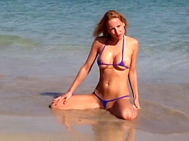 Hot blonde milf posing on public beach in string bikini