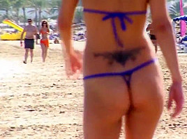 Hot blonde milf posing on public beach in string bikini