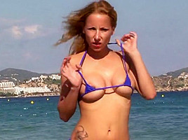 Hot blonde milf posing on public beach in string bikini