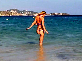 Hot blonde milf posing on public beach in string bikini