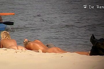 Two blondies are having a good time on the beach with naked boobs