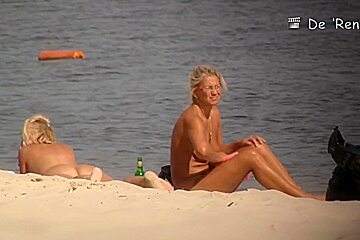 Two blondies are having a good time on the beach with naked boobs